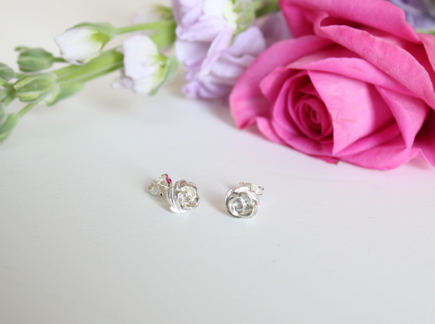 silver rose stud earrings surrounded by real flowers